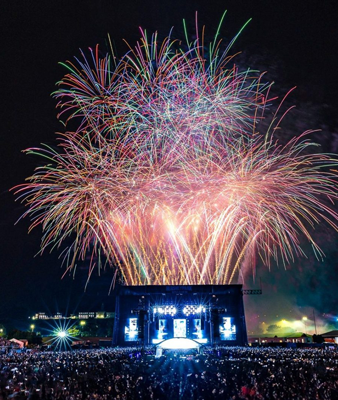 Massive beautiful blooming fireworks overtop a concert crowd