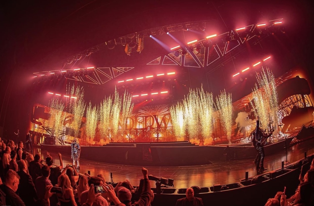 Carrie Underwood performs onstage at her Reflections Residency as warm lighting and vertical spark effects illuminate the background.