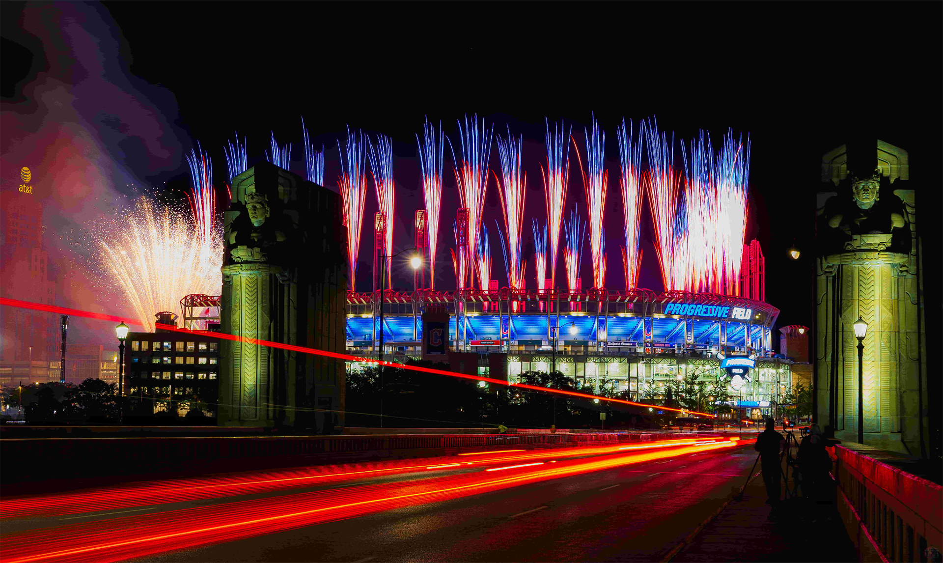 Red and blue pyrotechnic comets launch above Progressive Field during the Cleveland Guardians Rock n’ Blast celebration at night.