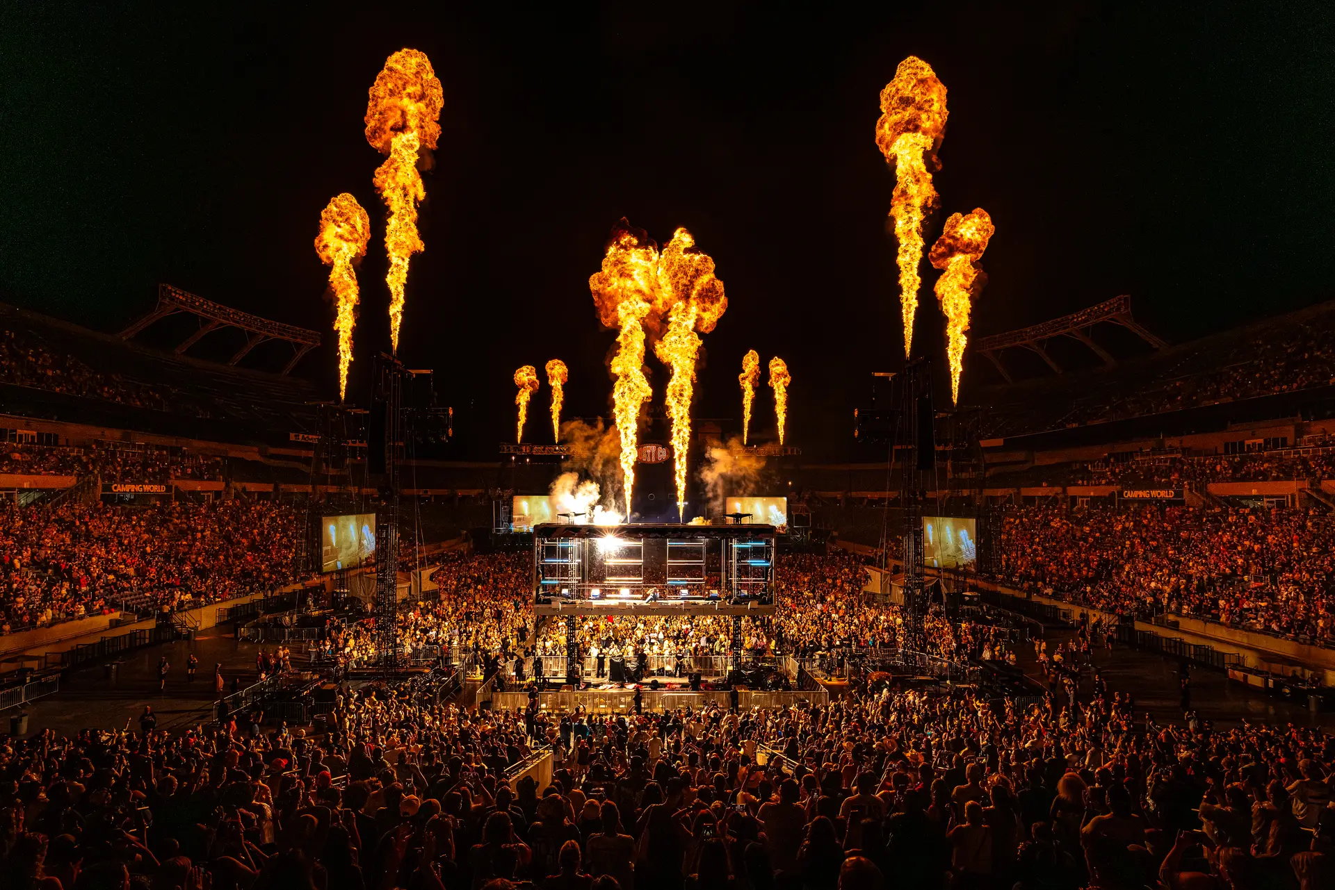 Post Malone performs at center stage as massive vertical flame effects erupt above a packed stadium during the Big Ass Stadium Tour.
