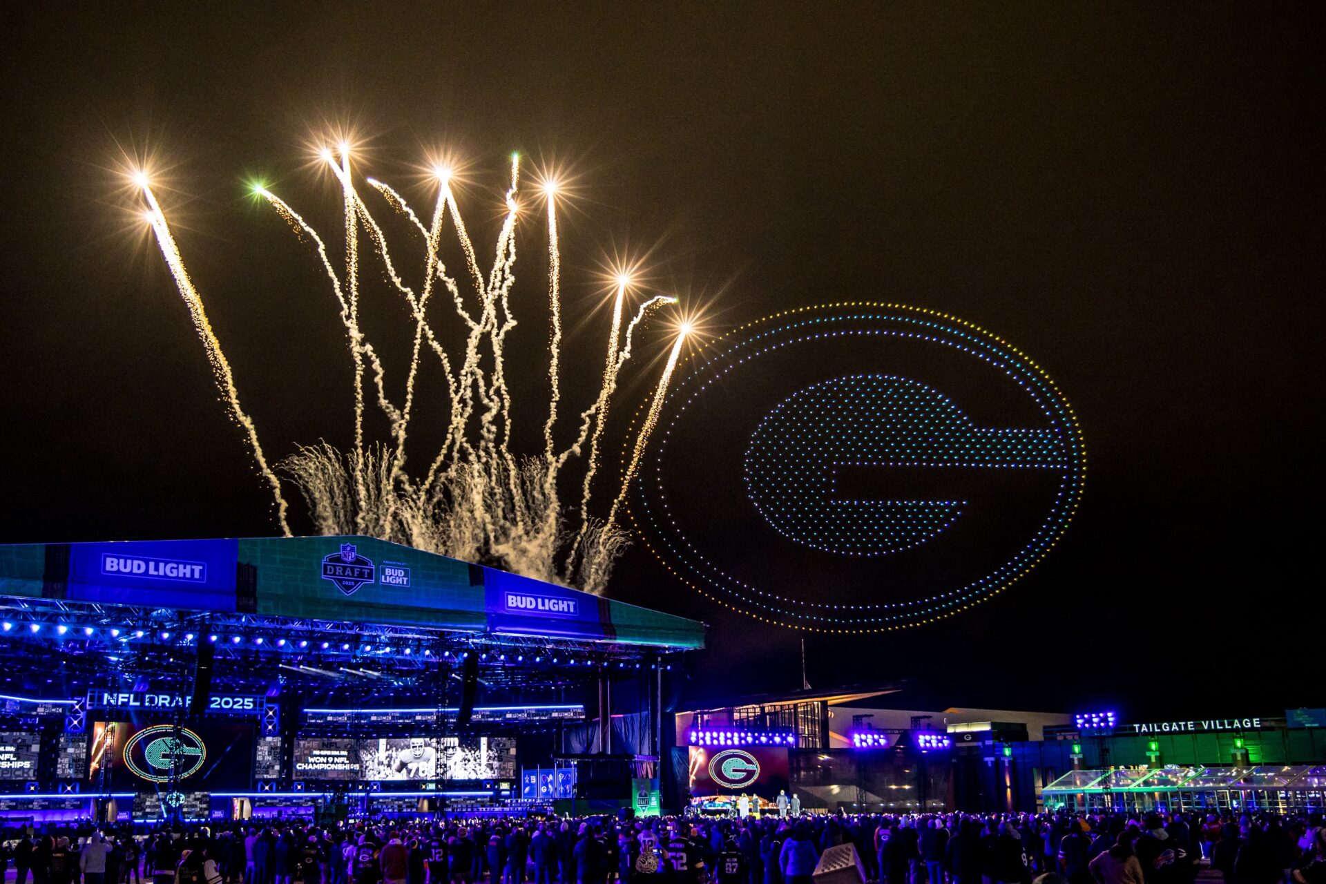 Green Bay Packers logo made of LED drones floating above stadium as golden fireworks burst in the sky
